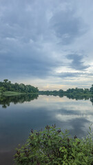 Obraz premium A deep river surrounded by trees and plants Thickets of reeds. Voluminous clouds