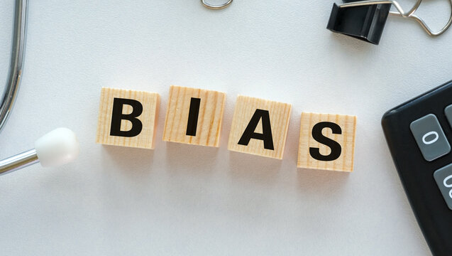 Wooden blocks spell BIAS on a clean white surface