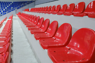 Rows of empty red plastic seats in a stadium tribune. © Microscope