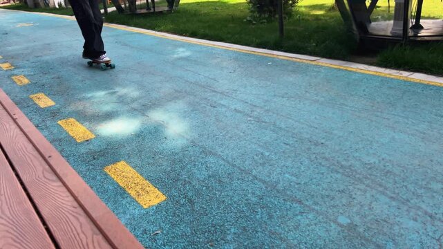 Close-up of skateboarder feet riding longboard on park path