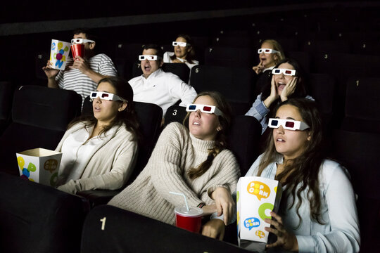 Scared people with 3d glasses watching a movie in a cinema