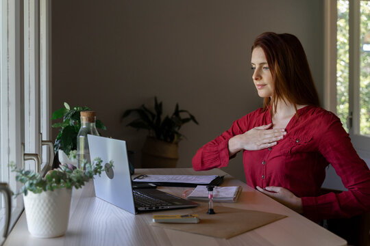 Doctor showing breathing therapy on video call through laptop while sitting at home