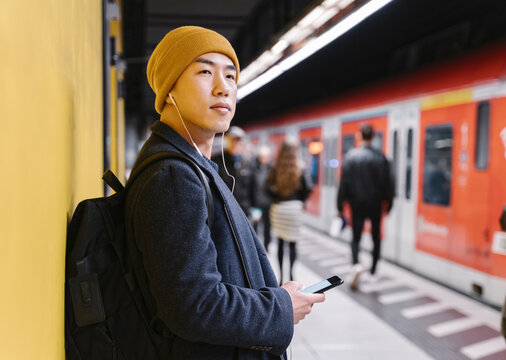 Stylish man with yellow hat and earphones in metro station