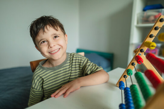 Smiling student studying mathematics with colorful abacus indoors