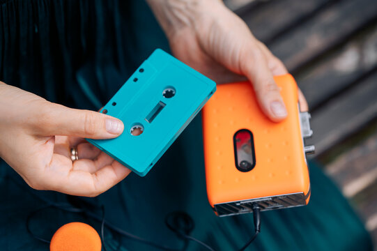 Hands holding retro audio player and cassette outdoors