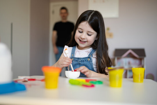 Smiling family playing with playdough at table indoors