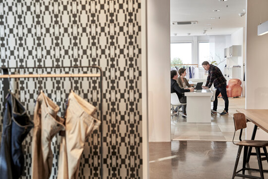 Owner discussing with customers at desk in clothing design studio
