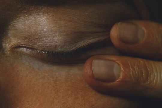 Close-up of fingers touching a closed eye during relaxation