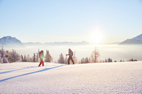 Austria, Tyrol, snowshoe hikers at sunrise
