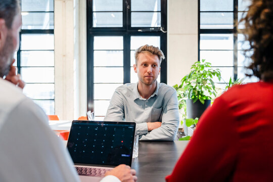 Young candidate with arms crossed giving job interview in office