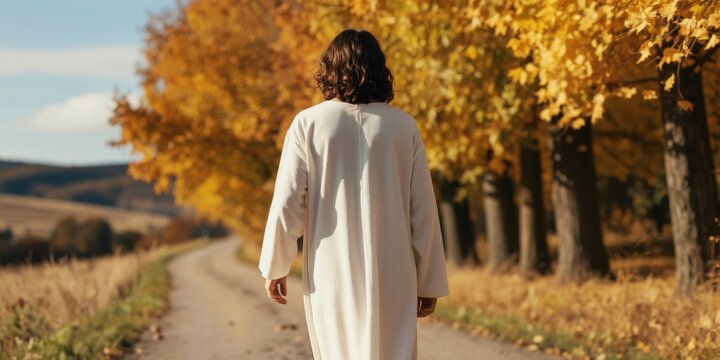 Man in white robe walks on dirt path past golden trees. Person follows autumn road under blue sky. Spiritual journey, divine guidance, seeking peace and hope.