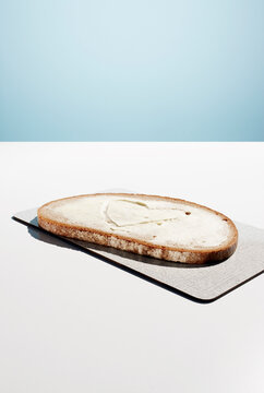Slice of bread with butter heart on a chopping board with copy space