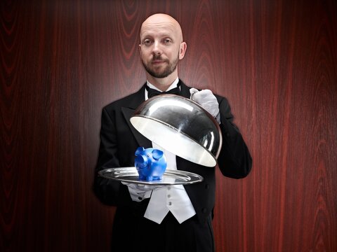 Butler presenting a blue piggy bank on a silver tray