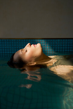 Beautiful woman floating in hot tub at spa