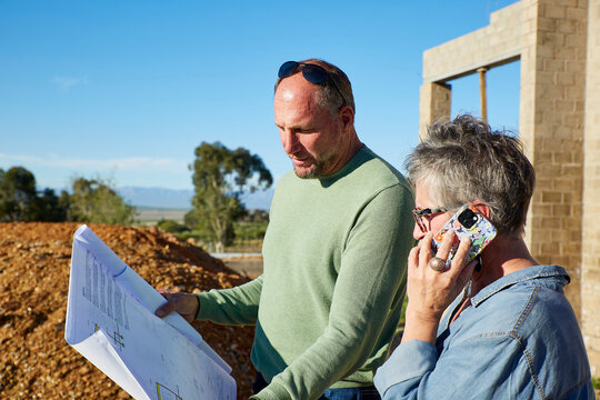 Builder and architect discussing plans at a building site