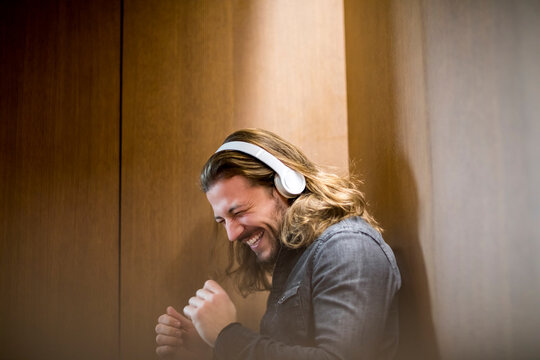Portrait of excited man listening music with headphones