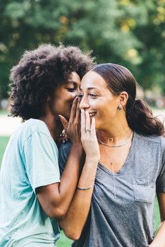 Two young women whispering in a park