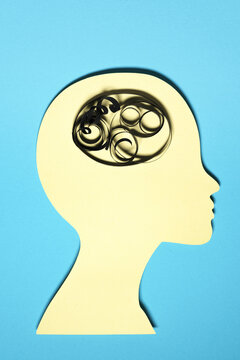 Paper cut out of human head with piece of string representing unordered thoughts