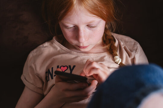 Child looking at smartphone experiencing screen addiction indoors