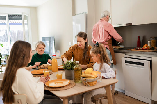 Happy family gathering for a meal in the kitchen