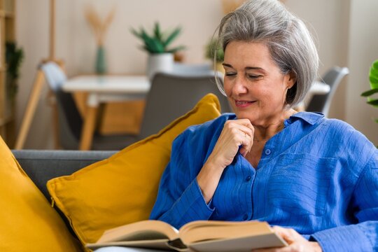 Smiling reader enjoying a good book on the sofa at home