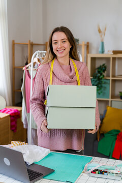 Smiling entrepreneur holding shipping boxes in a fashion studio