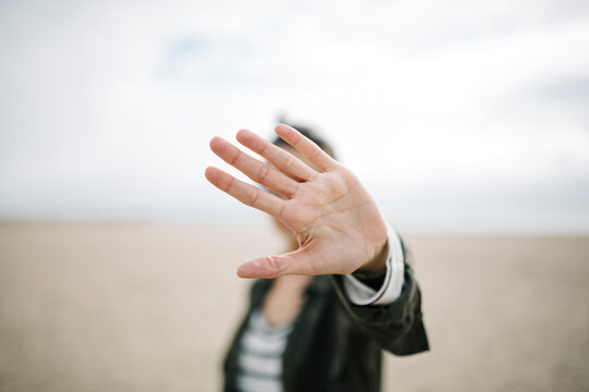 Young woman hiding face behind her outstretched hand