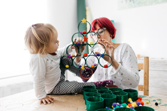 Mother and daughter doing crafts at home with accessories to make a Christmas tree