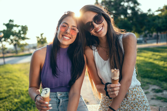 Friends eating ice cream and smiling in the park at sunset