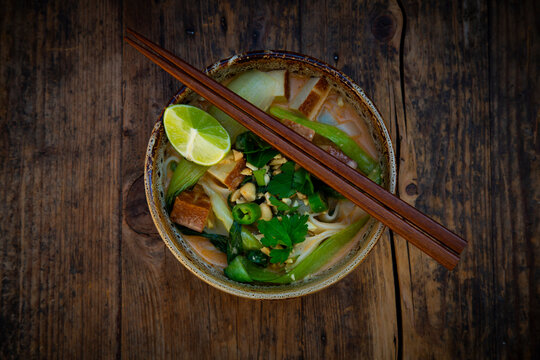 Thai curry soup with tofu and chopstick on wooden table