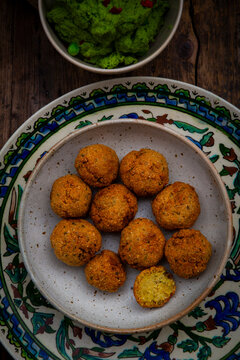 Falafel with pea hummus on an ornamented plate over dark wood