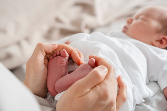 Mother holding newborn son's feet in hand