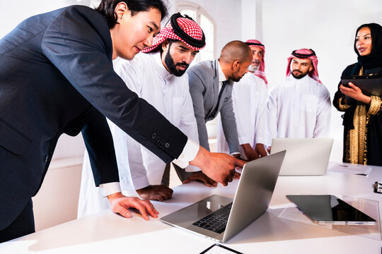 Diverse business team looking at laptop during meeting in office