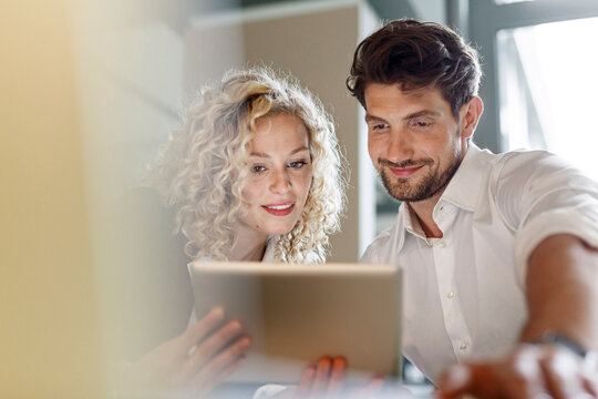 Two colleagues sharing tablet in office