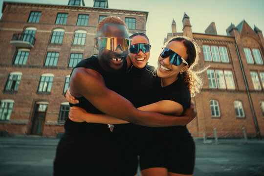 Close friends hugging after group run in urban setting
