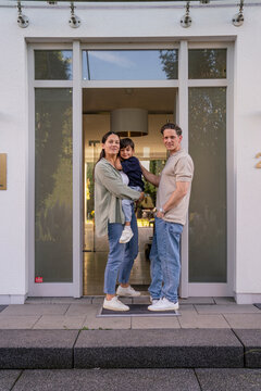 Family standing at home entrance showing togetherness and pride