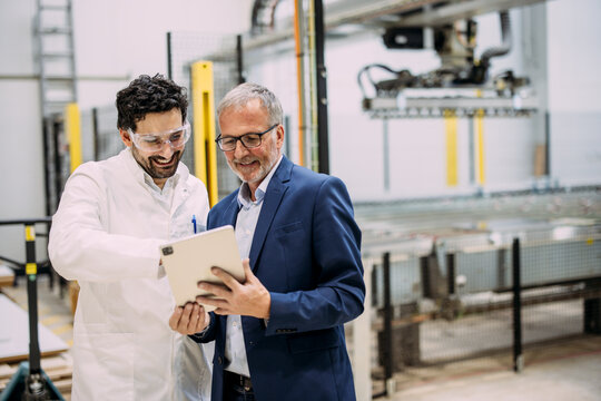Engineer and manager discussing plans on a tablet in a factory