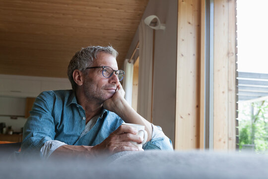 Mature man holding cup sitting on couch