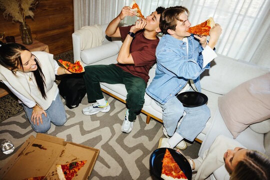 Group of friends enjoying pizza in a cozy living room setting