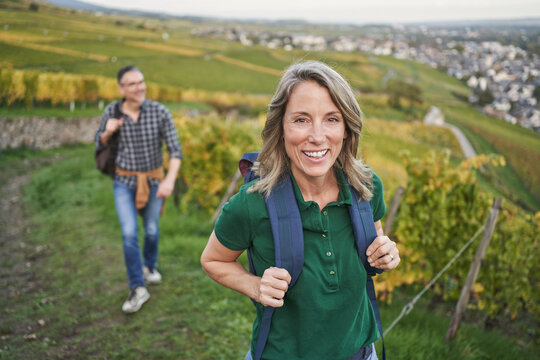 Happy woman with man in background walking on hill