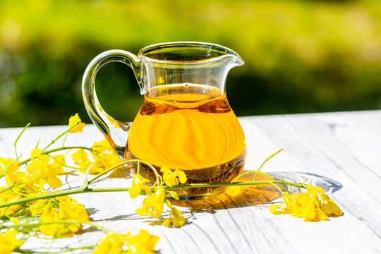 Rapeseed oil in jar with rape blossom on wood