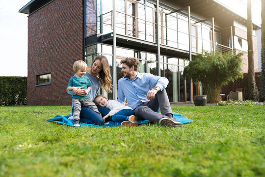 Happy family on blanket in garden in front of their home