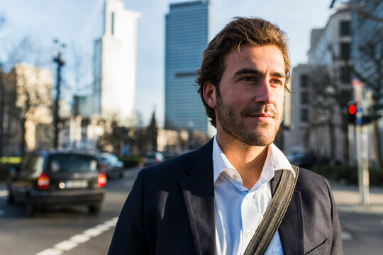 Germany, Frankfurt, Young businessman in the city with bicycle, using mobile phone