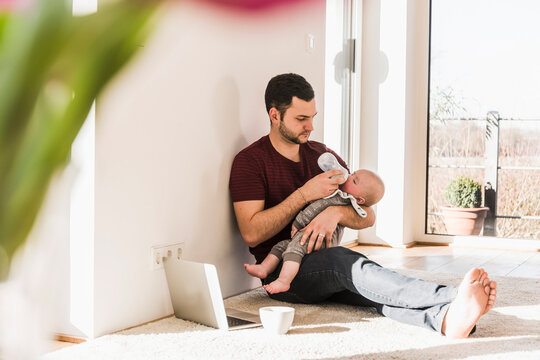 Father bottle feeding his baby son