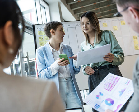 Business team discussing strategy with documents and mobile in modern office