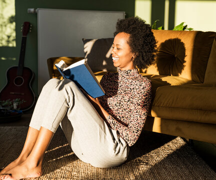 Woman relaxing at home and reading a book in the warm sunlight