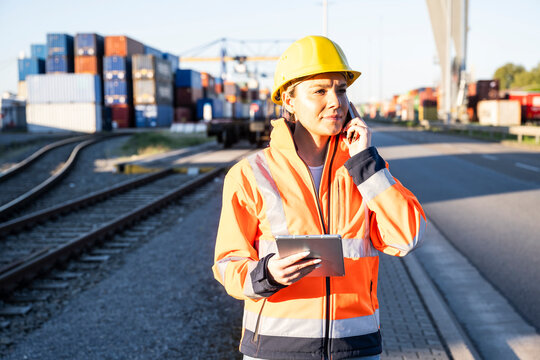 Logistics specialist with tablet and phone at shipping terminal
