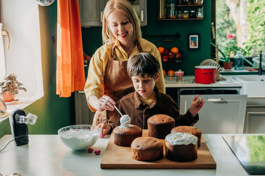 Mother and son glazing Easter bread in the kitchen