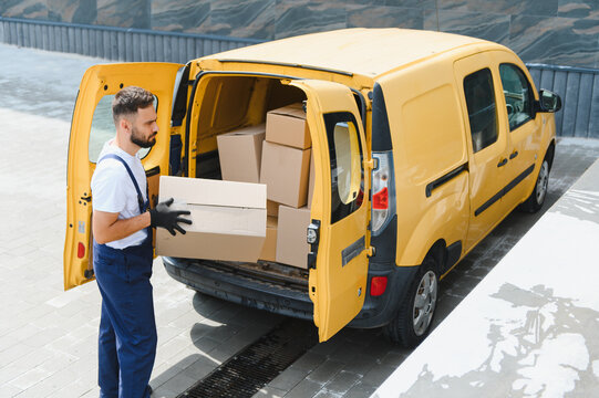 Courier unloading cardboard boxes from delivery van