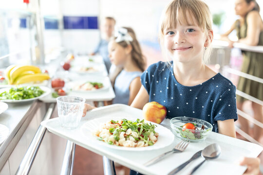 Smiling girl holding food tray in school cafeteria